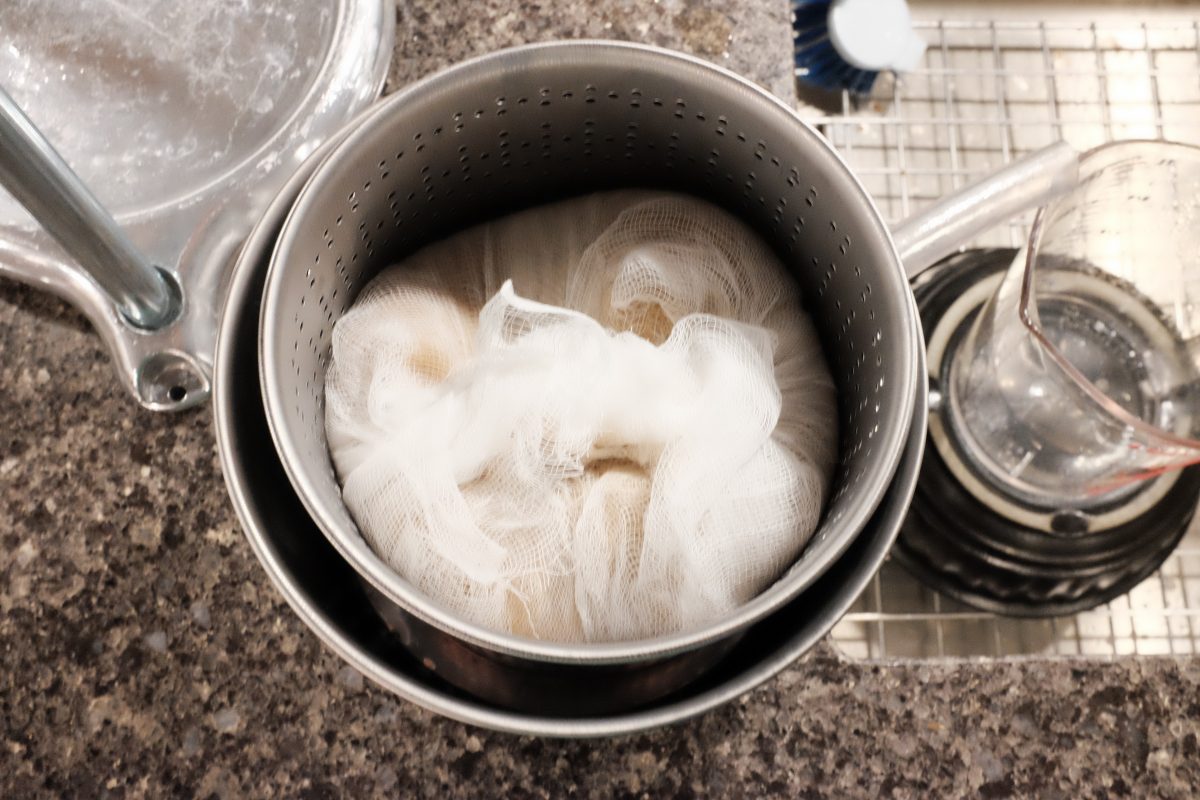 folding top of cheesecloth over the mash