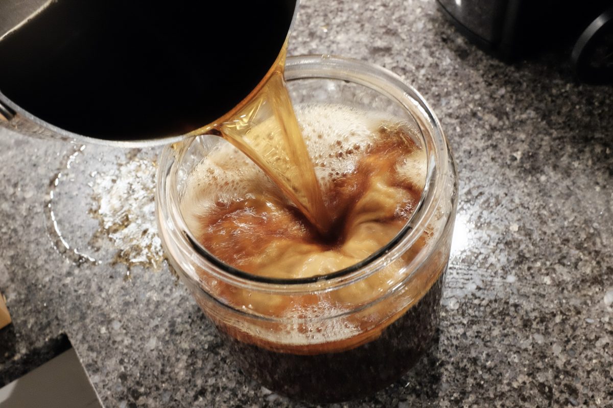 pouring brewed tea into fermenting container with kombucha scoby