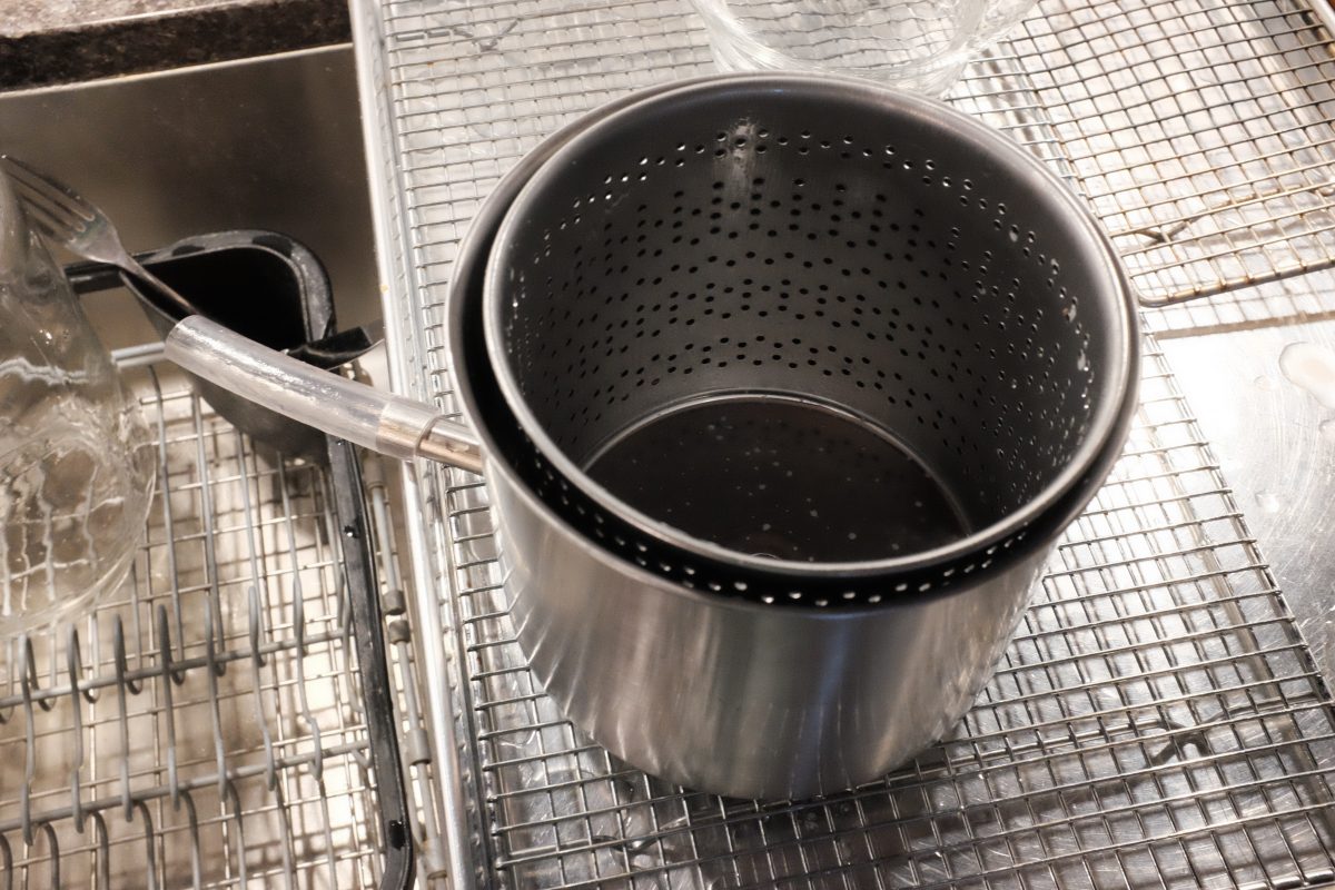 perforated basket inside bucket with spout. the inner part of fruit press.