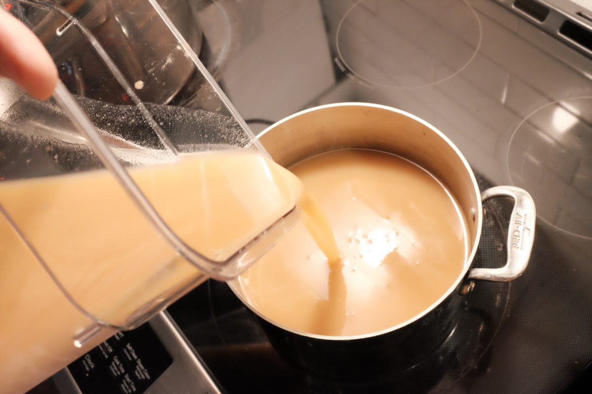 pouring pear juice into a pot on stove